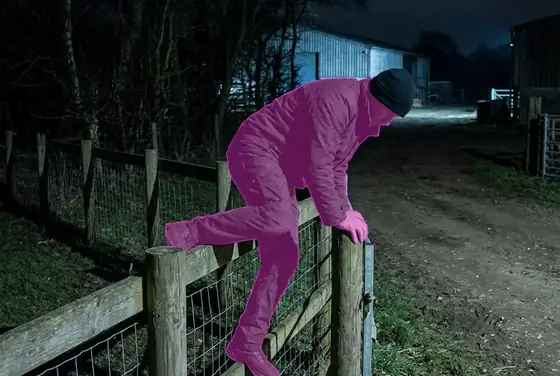 AI segmentation flagging a person climbing over a farm perimeter fence at night