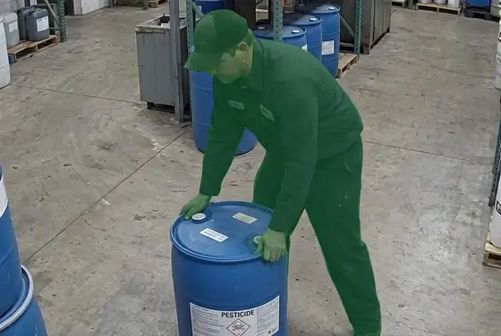 AI segmentation flagging a worker without chemical-resistant gloves handling a pesticide drum
