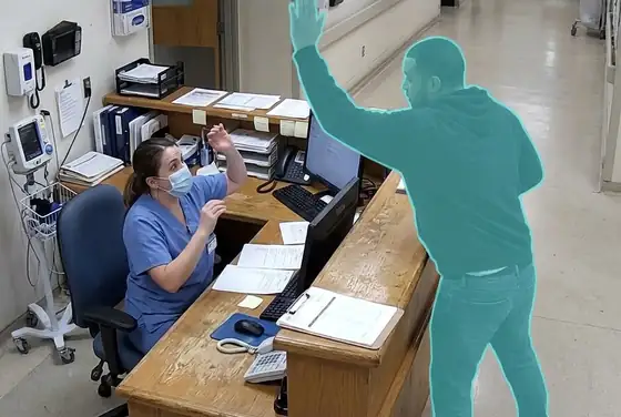 AI segmentation mask on a person raising a hand to strike a staff member at a triage desk