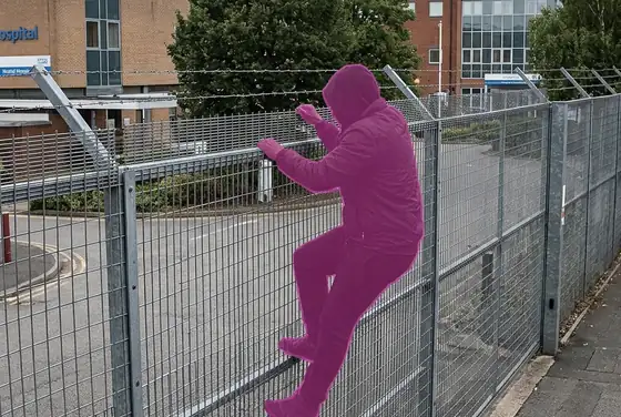 AI segmentation mask on a person climbing a hospital perimeter fence