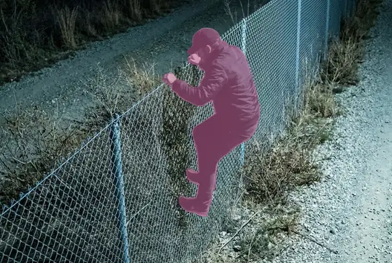 AI segmentation mask on a person crossing the perimeter fence line at night