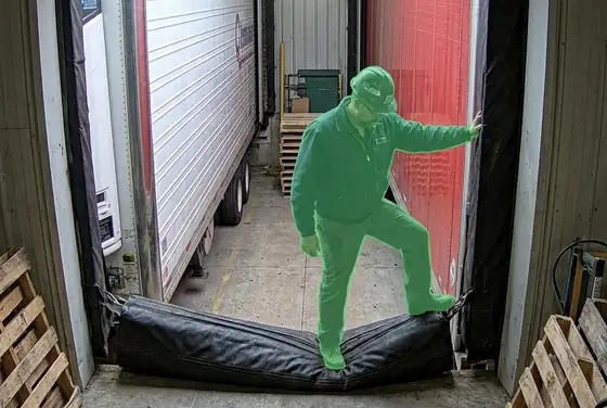 AI segmentation mask on a worker climbing over a dock seal between trailers