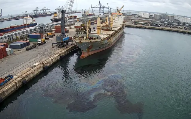 An oil and water spill spreading across a concrete factory floor