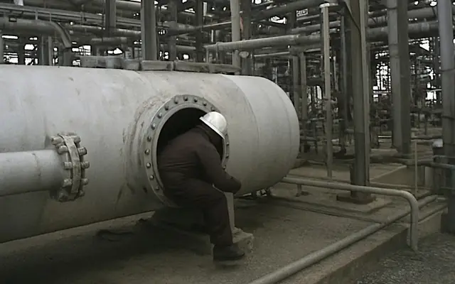 A worker opening a manhole on top of a process vessel without a permit posted