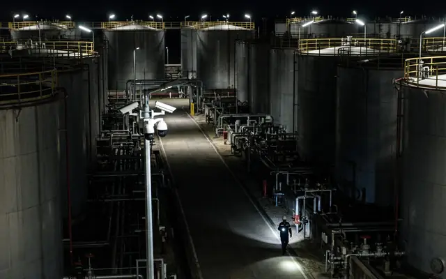 A tank farm at night with only a few pools of light and large dark areas