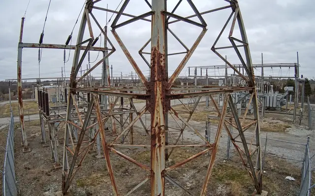 Heavy rust scaling at the base of a lattice transmission tower near ground level