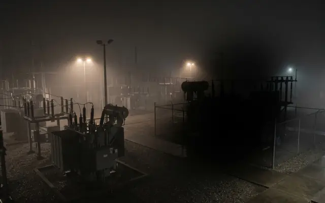 A large solar farm and switchyard at night with most of the field in darkness