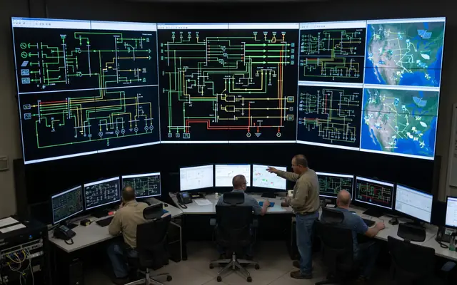 A wall monitor showing a live grid operations dashboard with substations, solar fields and alerts