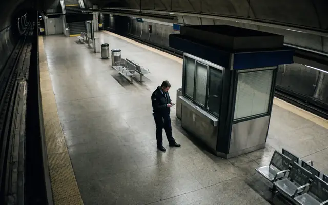 A single worker isolated in a remote corner of a large industrial site at dusk